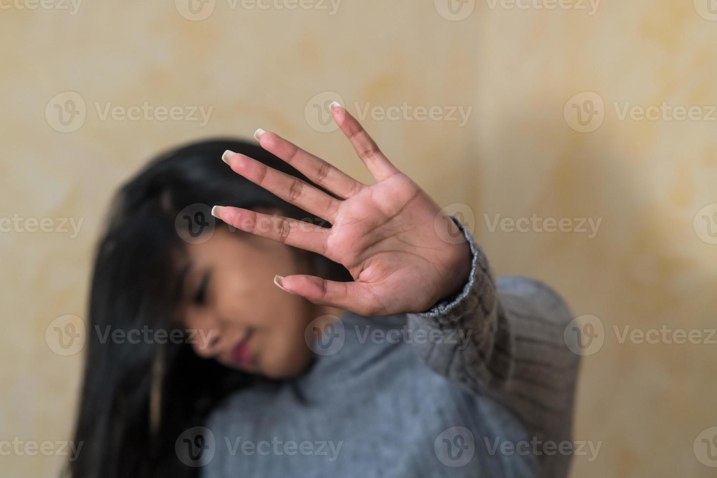 Self defence young Indian woman covering her face with hand photo