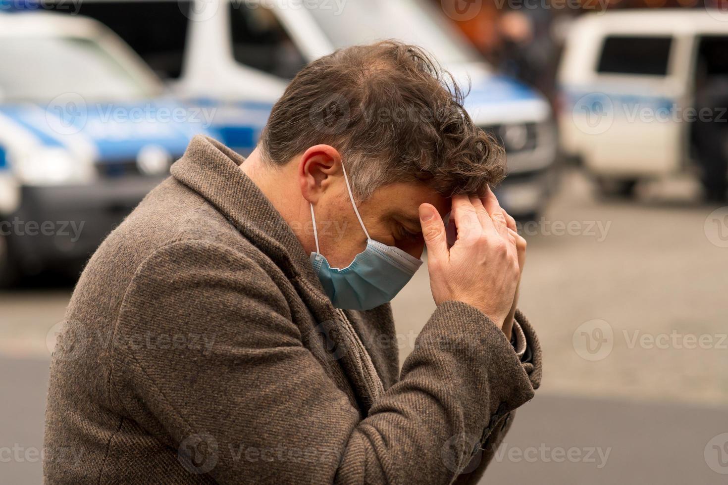 A man wearing a medical protective mask with his hands on his head due to receiving bad news or a headache photo