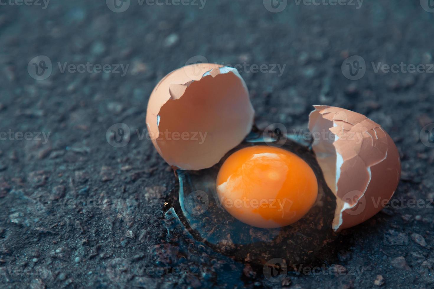 Huevo roto sobre asfalto como símbolo de fracaso foto