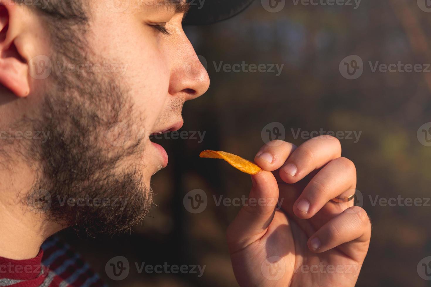 hombre barbudo en el bosque comiendo patatas fritas foto