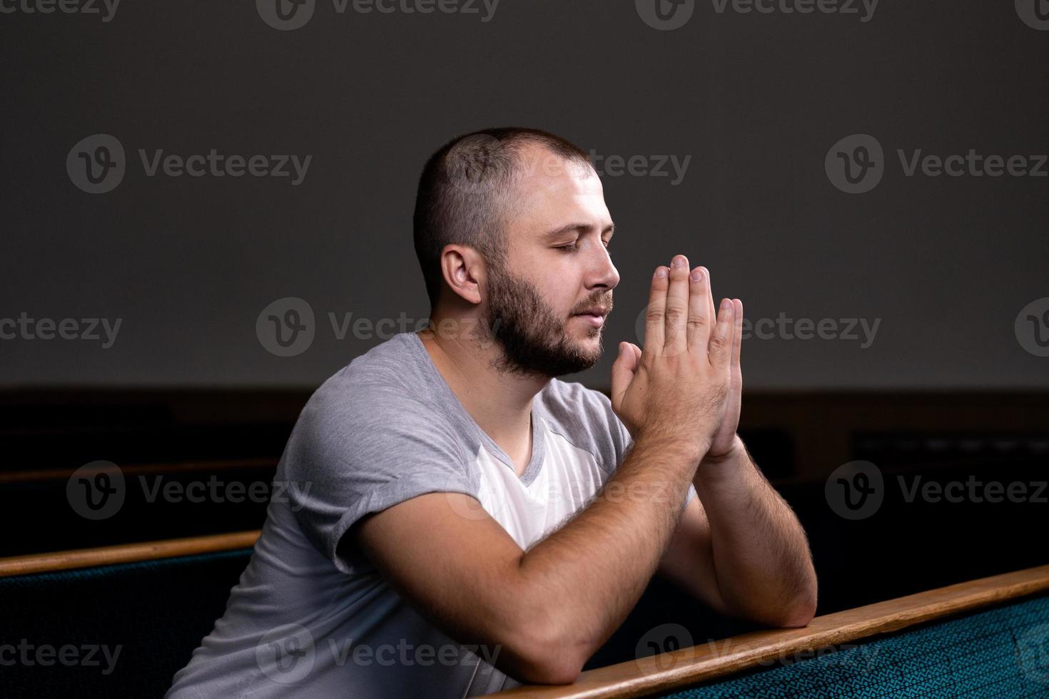 A Christian man in white shirt is sitting and praying with humble heart in the church photo