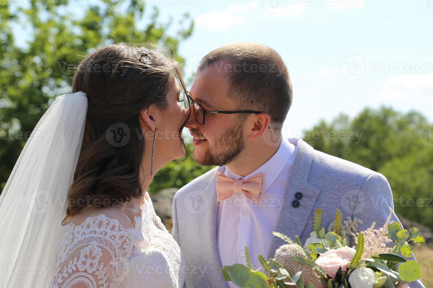 Foto de boda de la novia y el novio en un color rosa grisáceo en la naturaleza en el bosque y las rocas