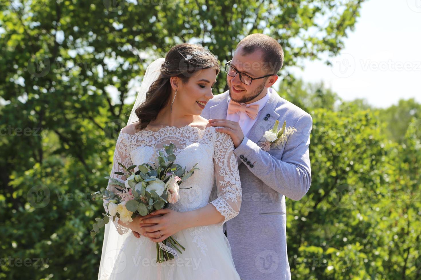 Foto de boda de la novia y el novio en un color rosa grisáceo en la naturaleza en el bosque y las rocas