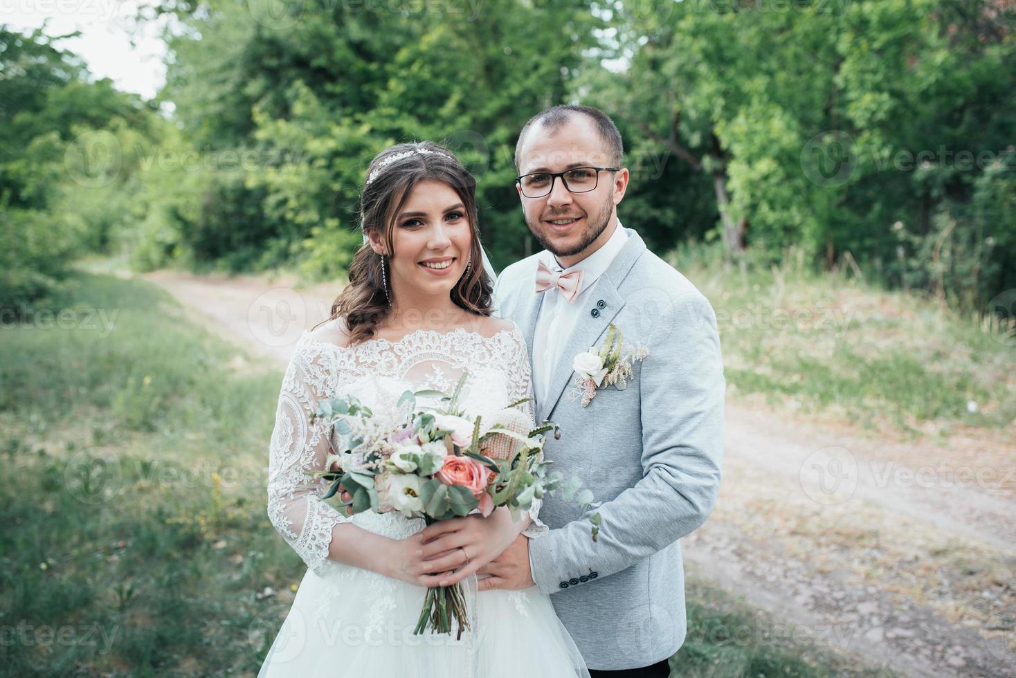 Foto de boda de la novia y el novio en un color rosa grisáceo en la naturaleza en el bosque y las rocas