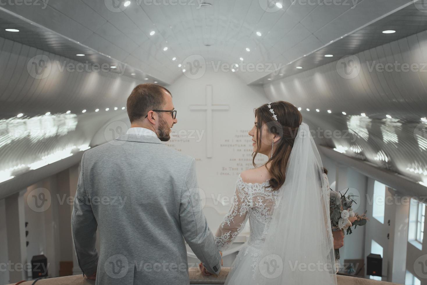 La joven novia y el novio en el día de su boda en un edificio de la iglesia foto