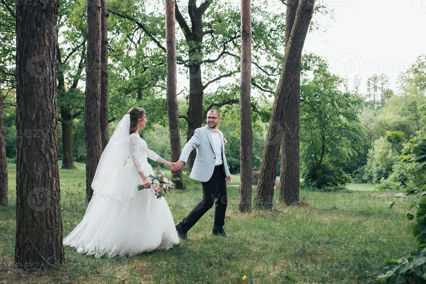 Bride and groom are walking in the woods on their wedding day photo