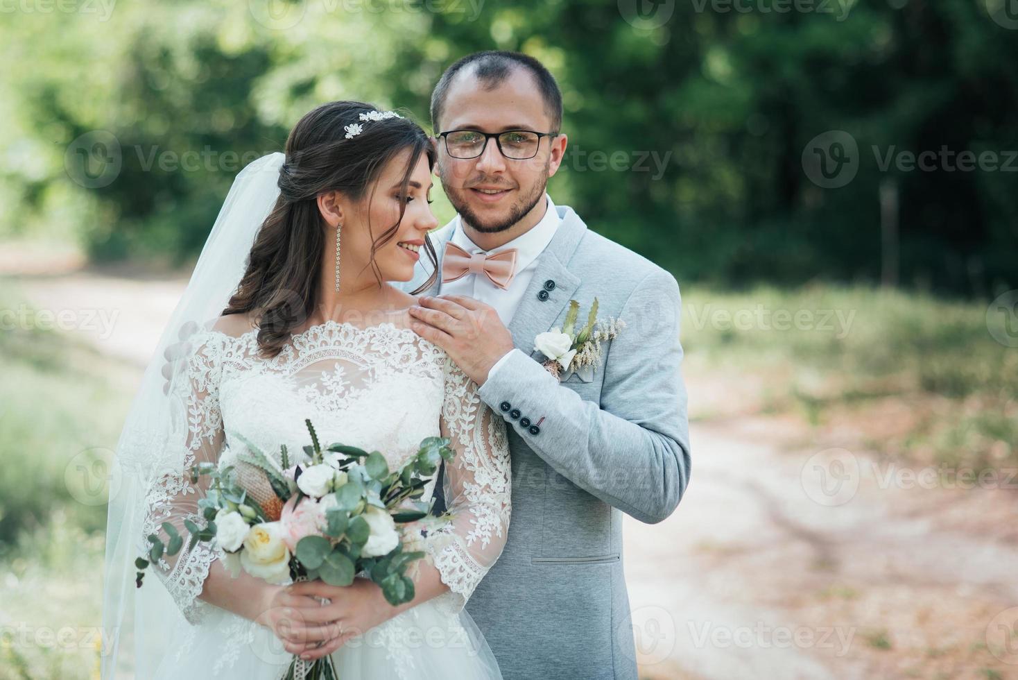 Foto de boda de la novia y el novio en un color rosa grisáceo en la naturaleza en el bosque y las rocas