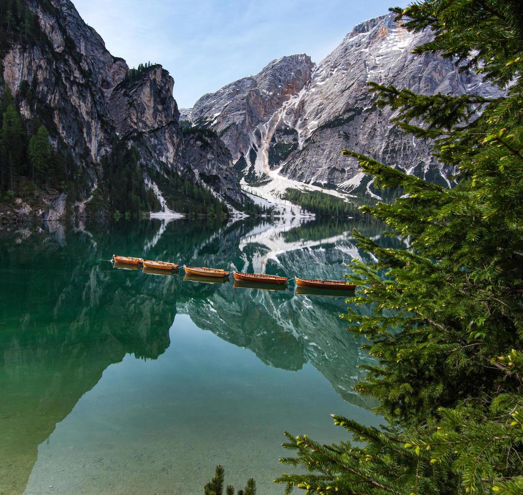 Un alto ángulo de vista de los barcos con el monte seekofel reflejándose en las claras y tranquilas aguas del icónico pragser wildsee lago di braies en dolomitas foto