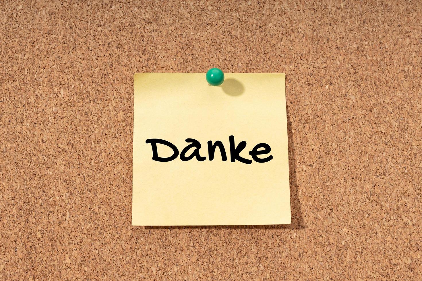 Danke - Thanks word in German language on yellow note on cork board photo