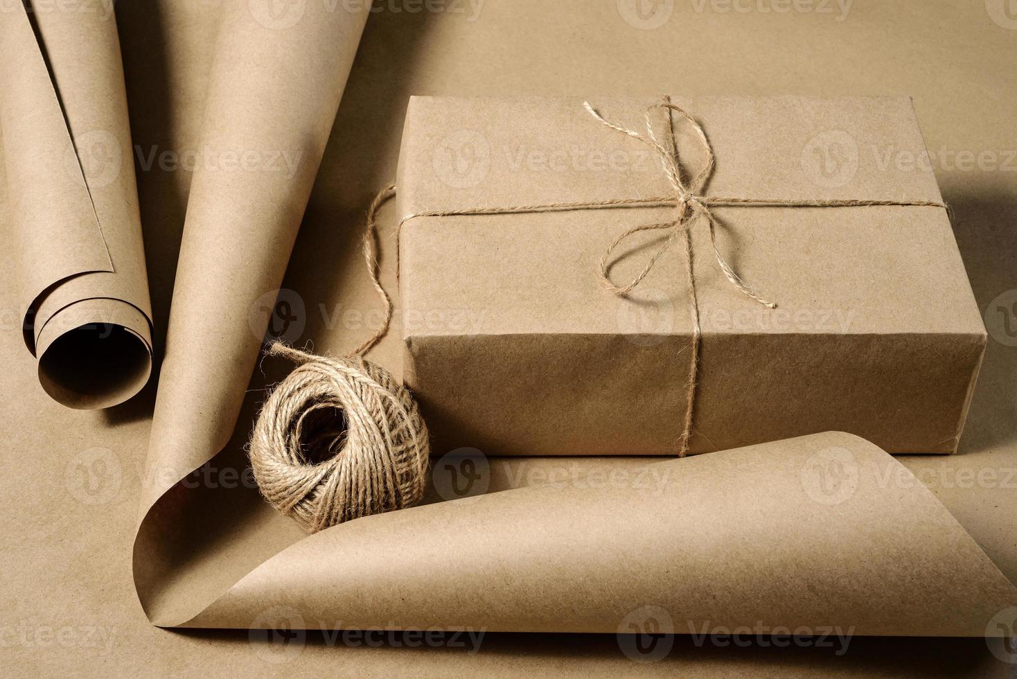 A box wrapped in craft paper a roll of paper and a skein of twine photo