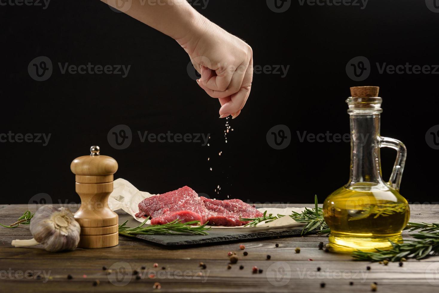 Hand sprinkle salt on beef steaks photo