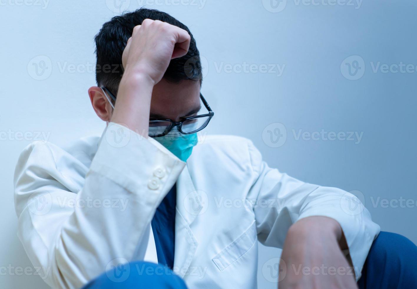 Retrato de joven médico caucásico en bata blanca que se siente estresado y tiene síndrome de agotamiento foto