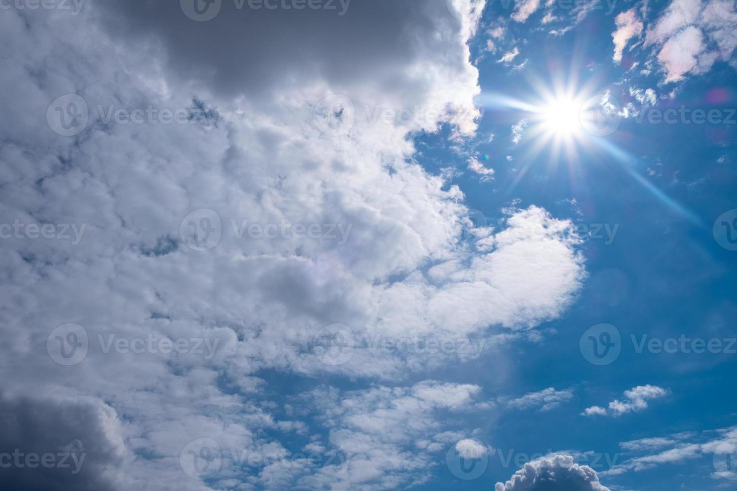 White sun with clouds on blue sky photo