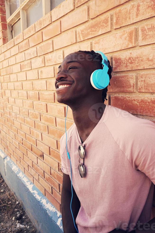 joven, recostado, en, pared ladrillo, llevando, auriculares foto