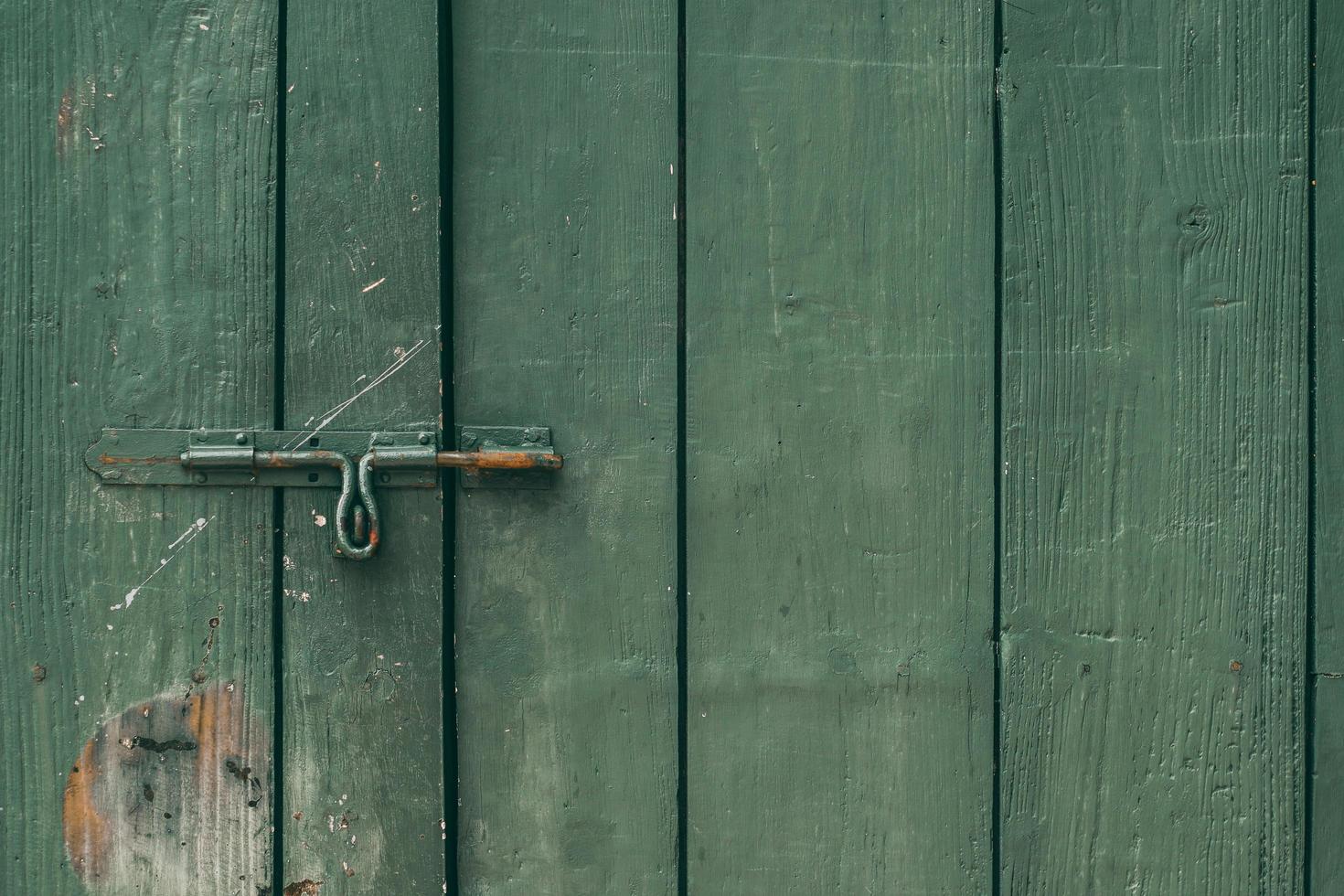 El pestillo de la puerta vieja y oxidada y la cerradura de la puerta de madera verde foto