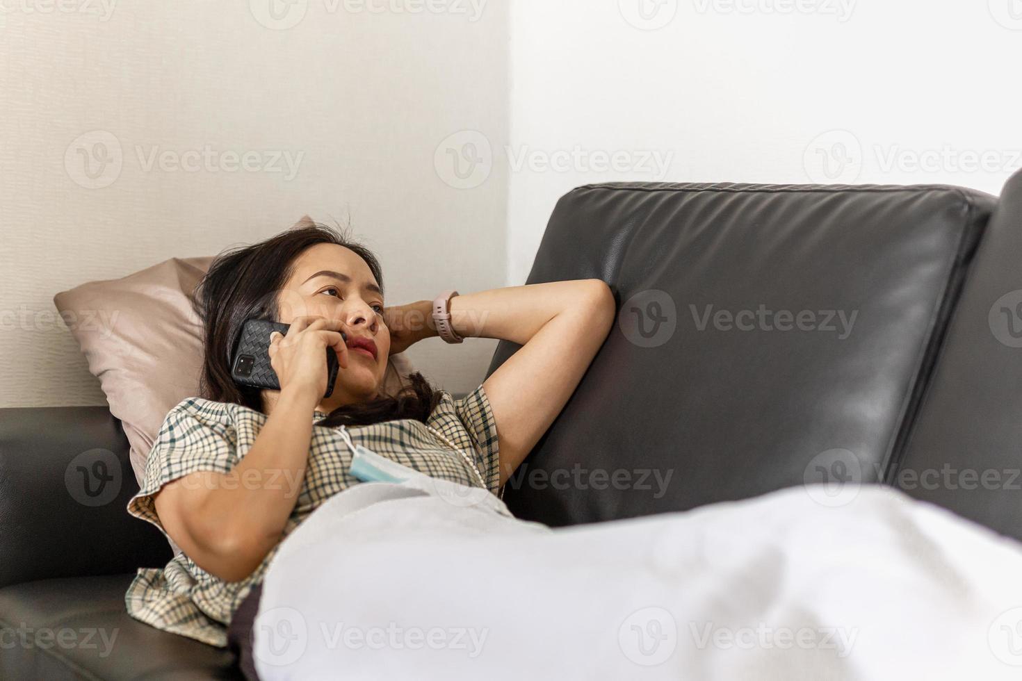 Woman lying on a couch talking on smartphone quarantine concept photo