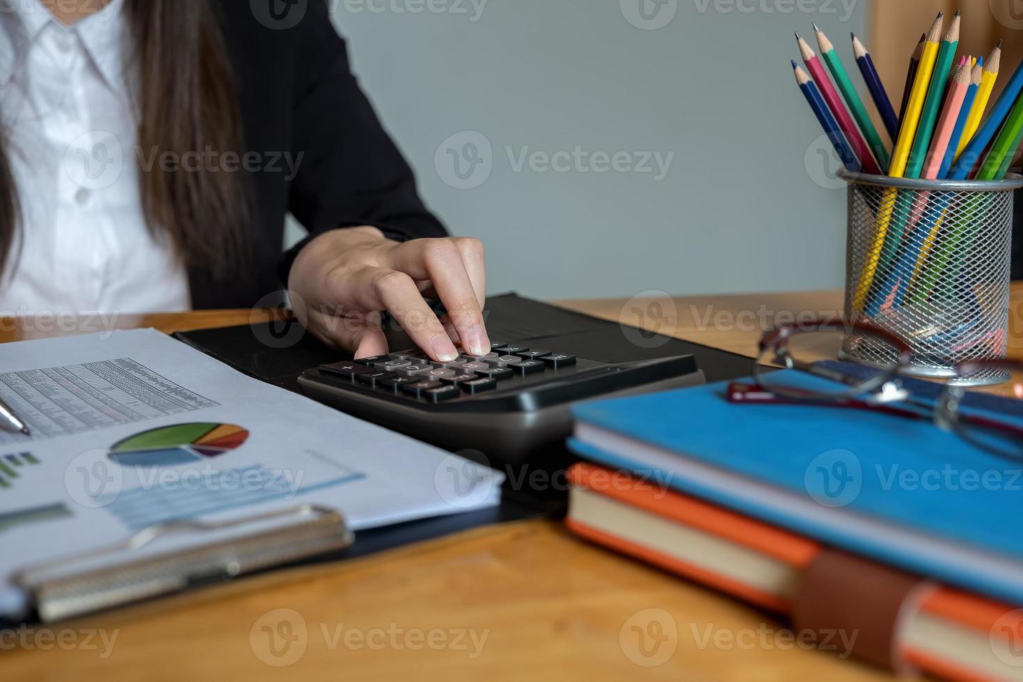 La empresaria o los contadores están trabajando en la oficina para verificar la precisión de la cuenta usando la calculadora para calcular el análisis de datos. foto