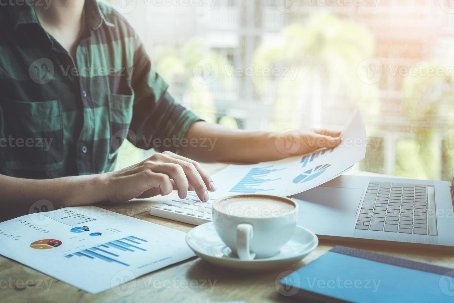 The accountant is pressing the calculator to calculating check the accuracy of the investment budget with using computer laptop and document data to analysis photo