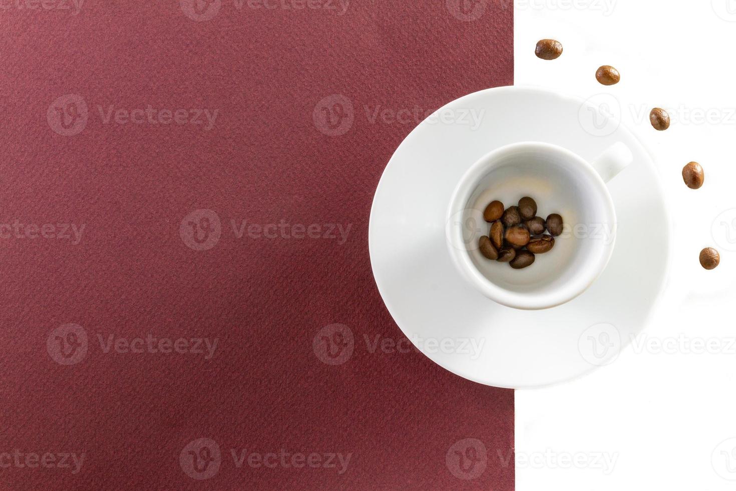 Vista superior de una taza de café y granos de café sobre fondo blanco y marrón foto