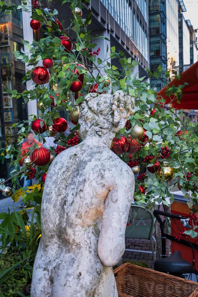 Una estatua y un árbol en la decoración navideña en el área de desarrollo moderno de Spinningfields en Manchester, Inglaterra foto