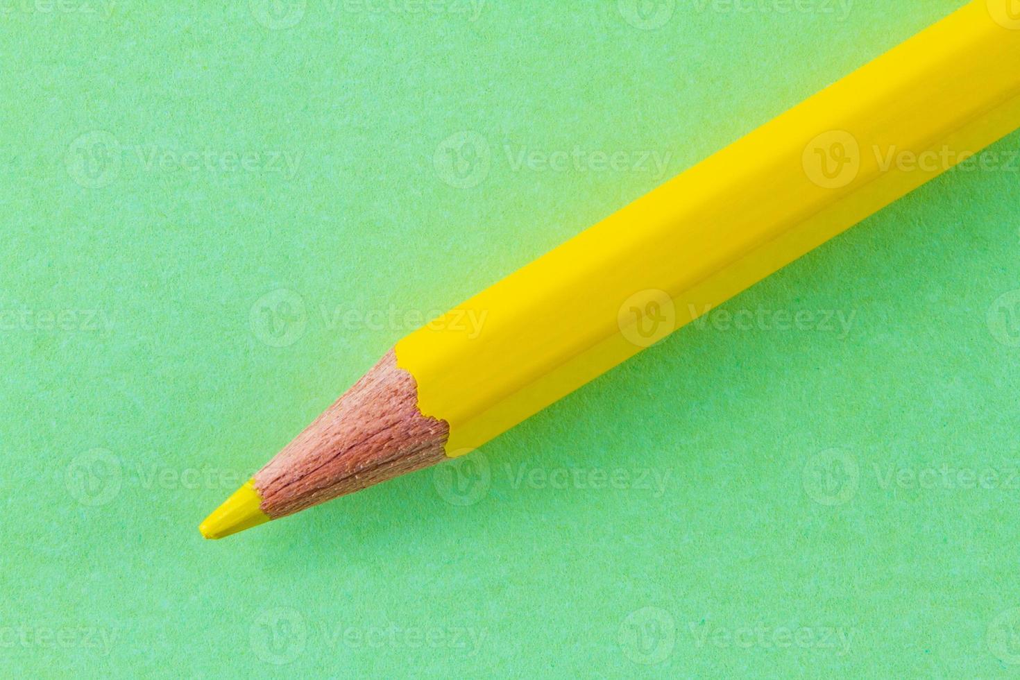 Yellow color pencil on green color paper arranged diagonally photo