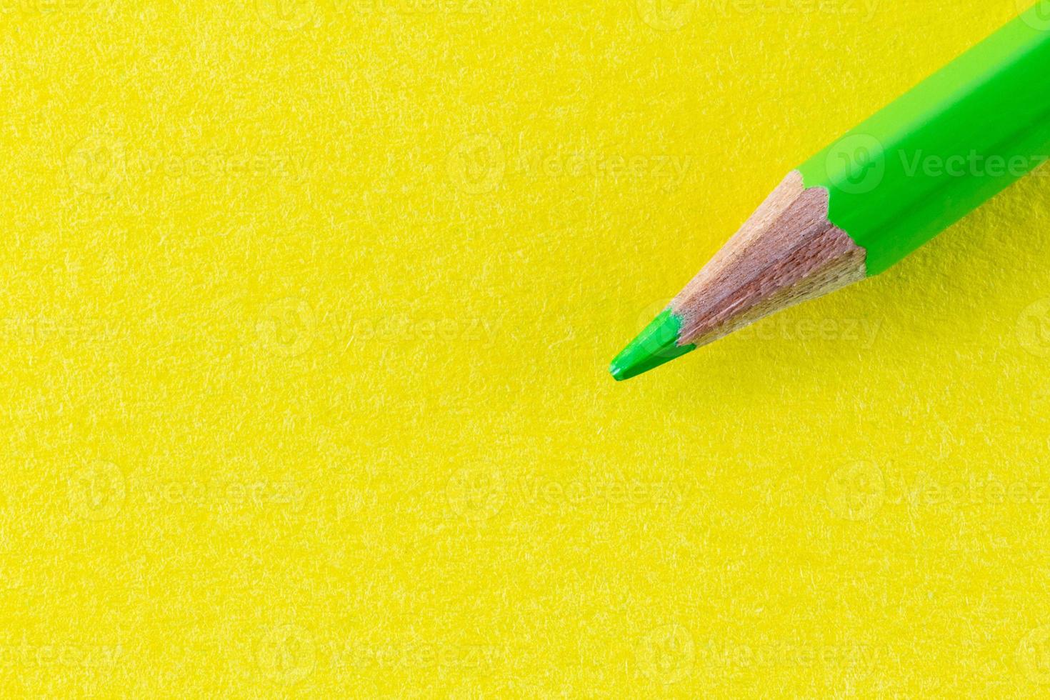 Green color pencil on yellow color paper arranged diagonally photo