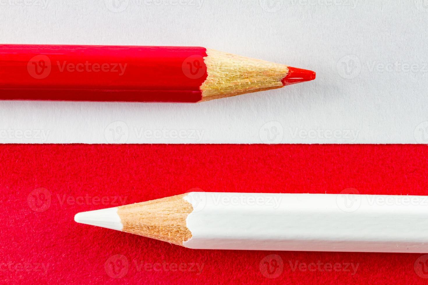 Color pencils on red and white color papers arranged horizontally photo