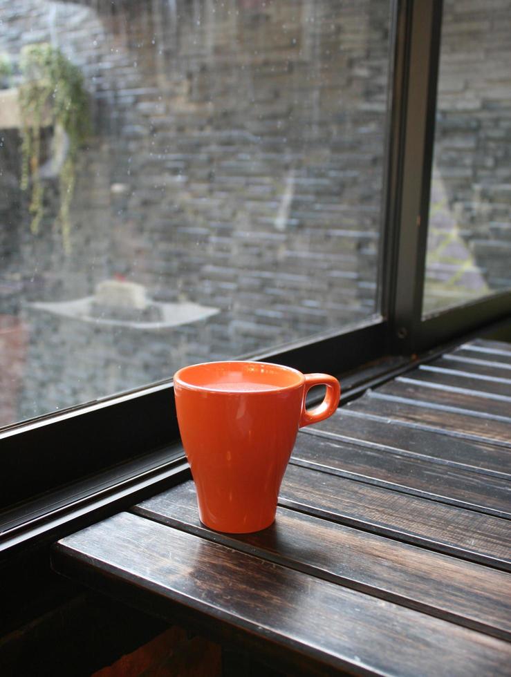 Milk in orange mug on wood table in coffee shop photo