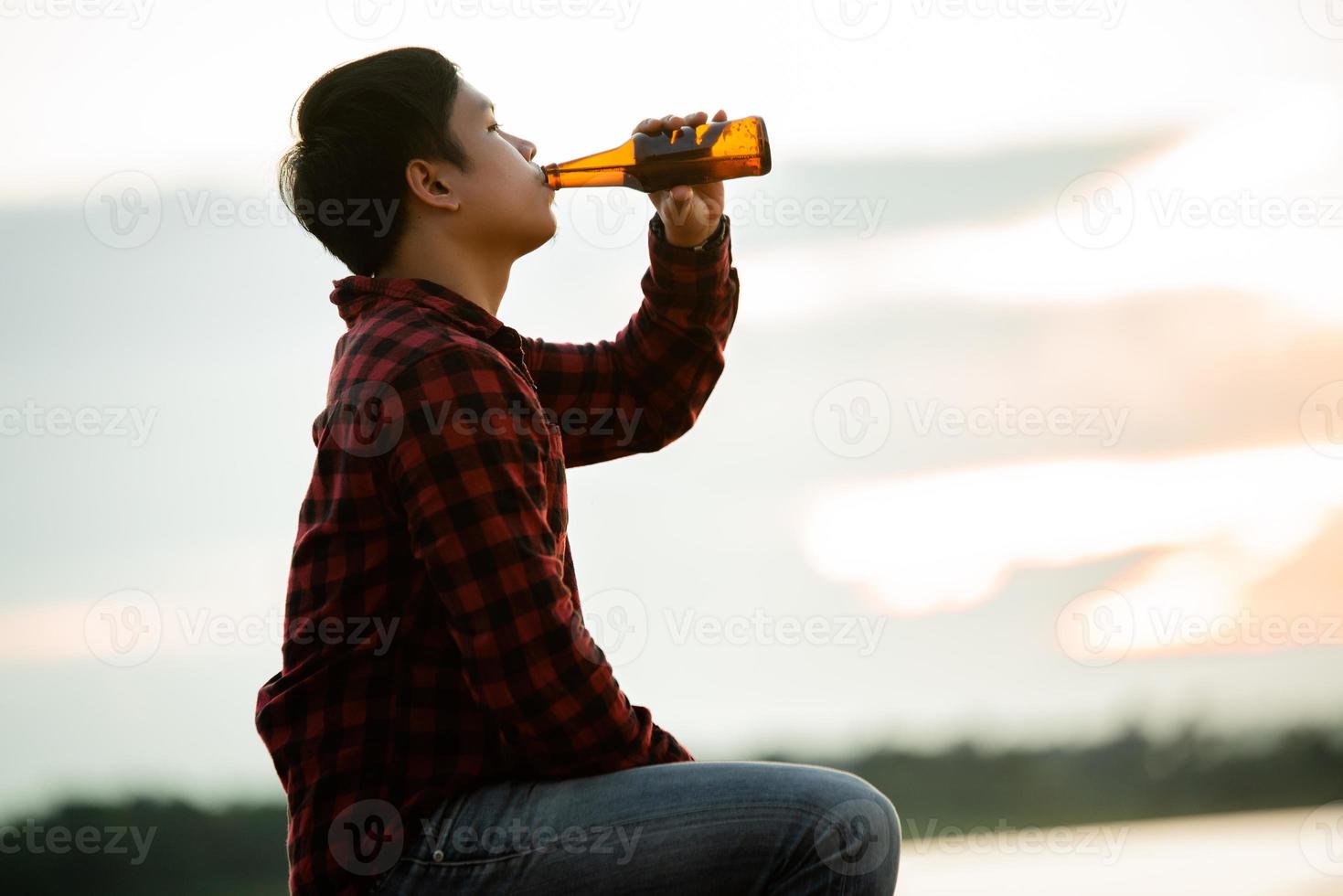 silhouette man holding beer with sunset background photo