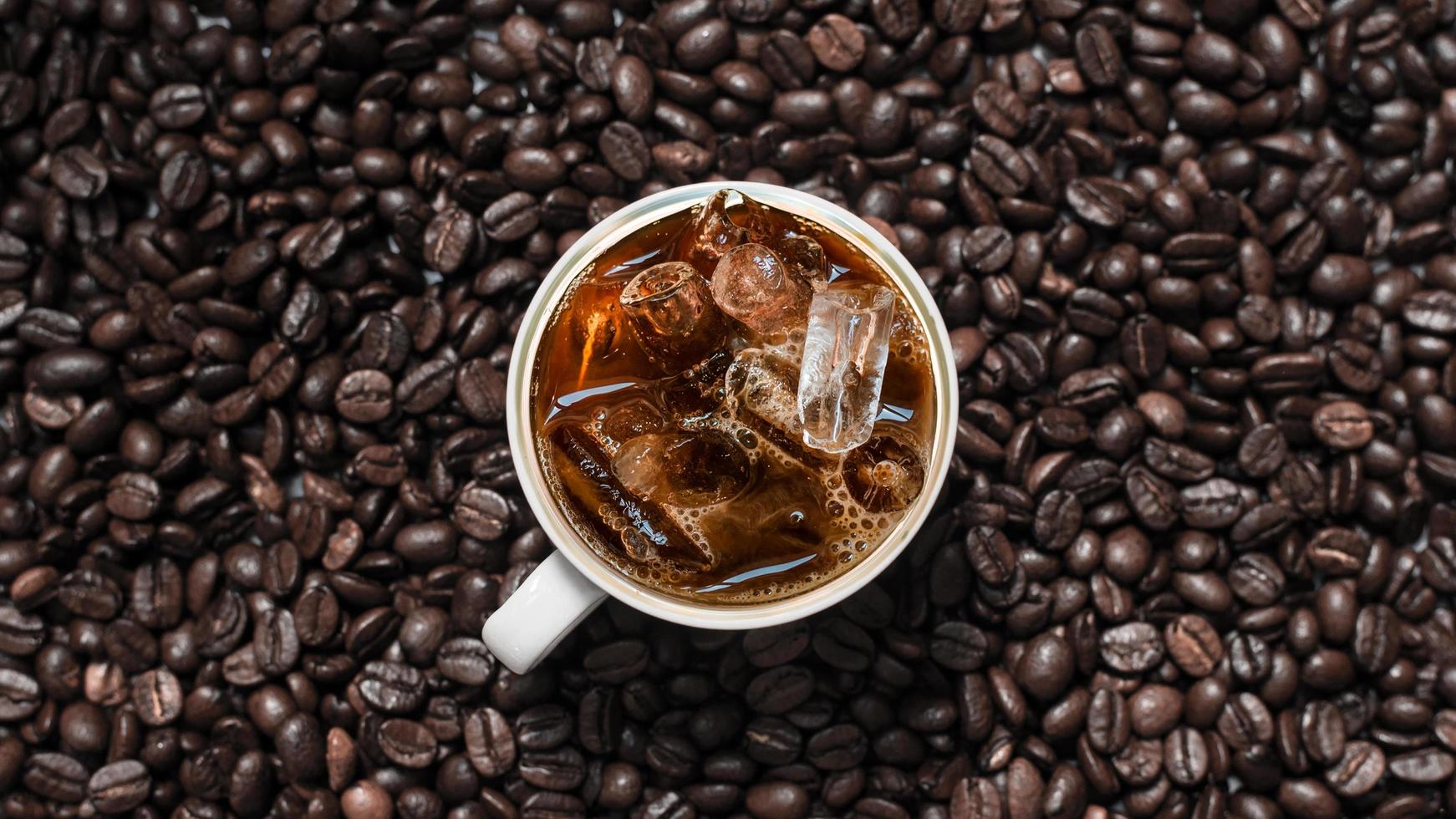 Top view of iced coffee in pile of coffee beans photo