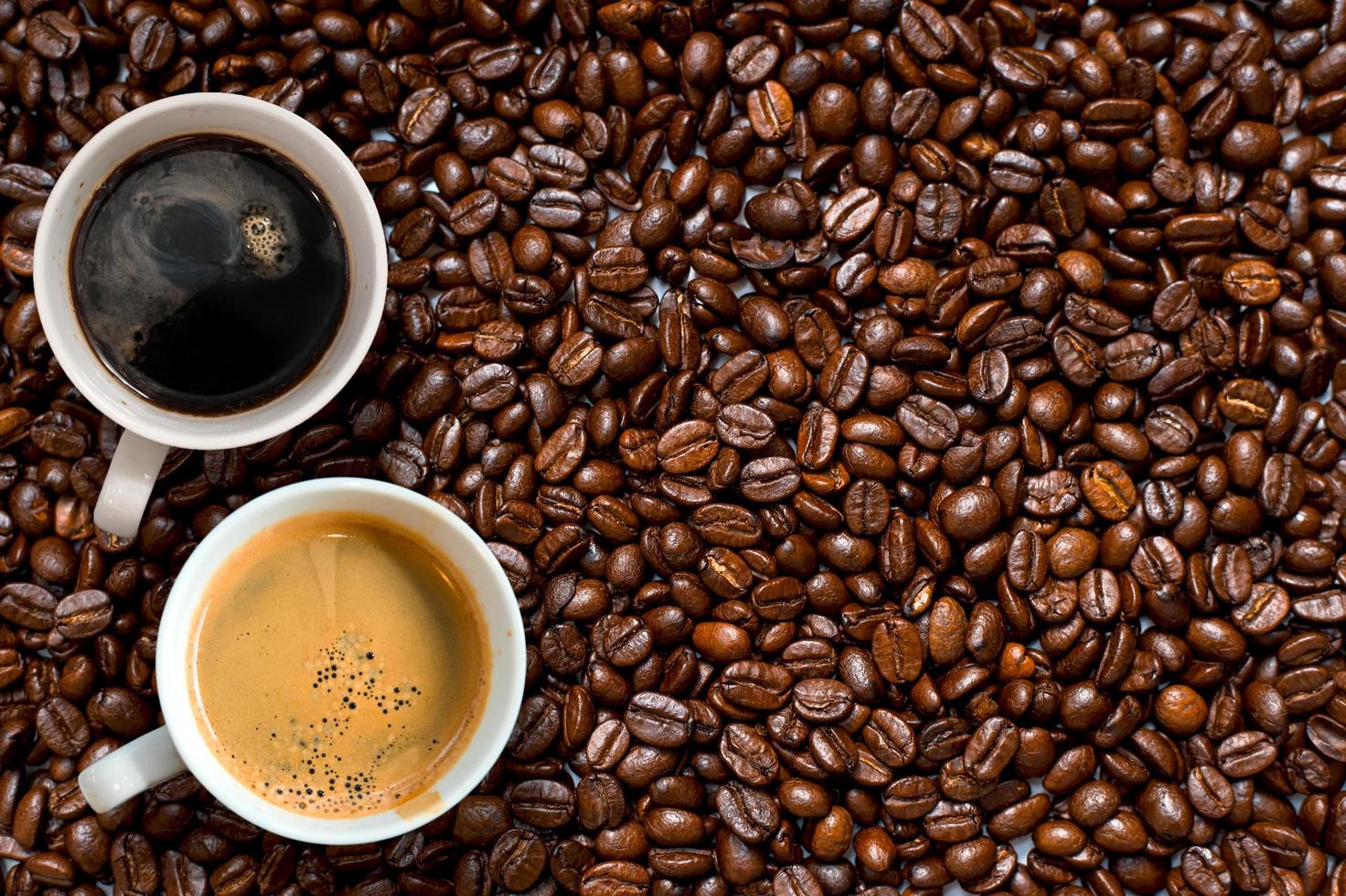 Top view of two cups of coffee in pile of coffee beans photo