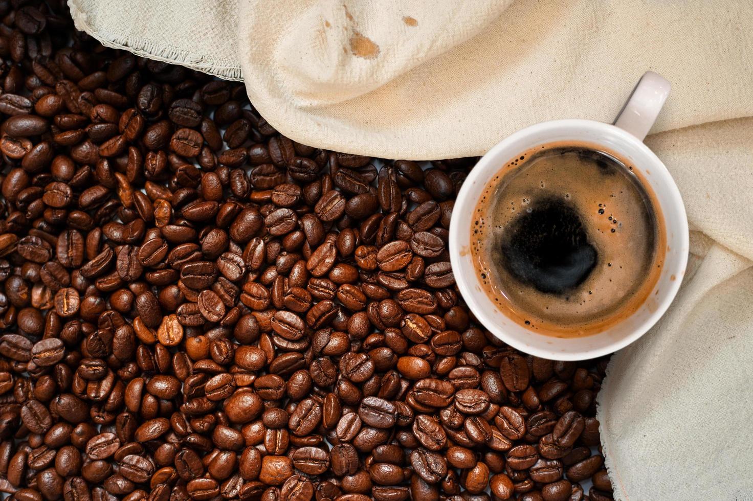 Top view of cup of coffee in pile of coffee beans photo