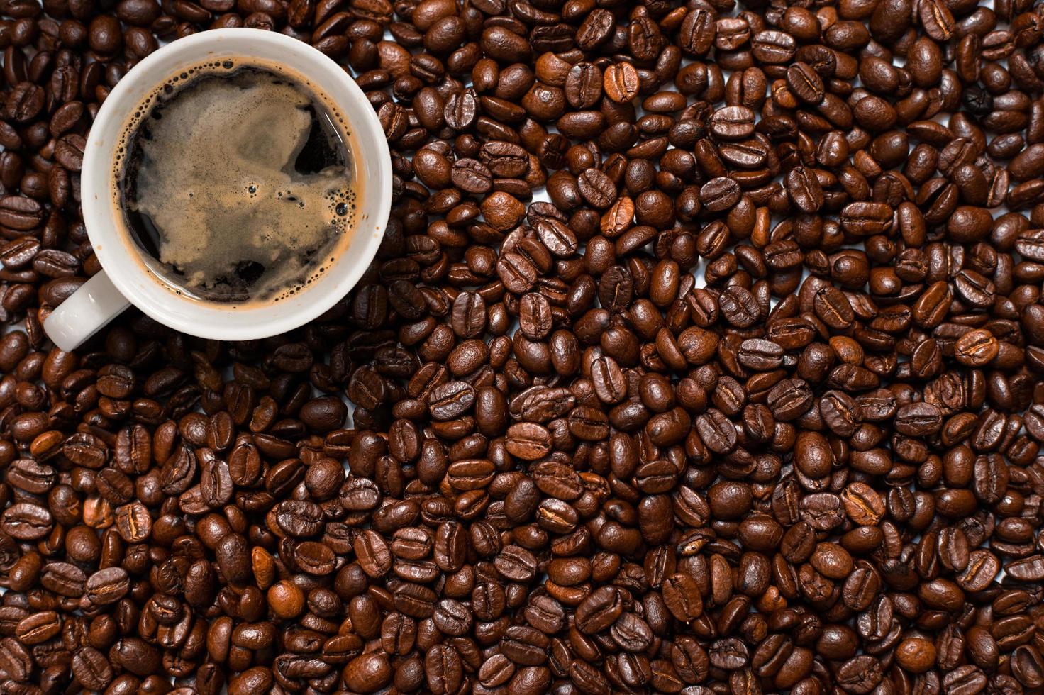 Top view of cup of coffee in pile of coffee beans photo