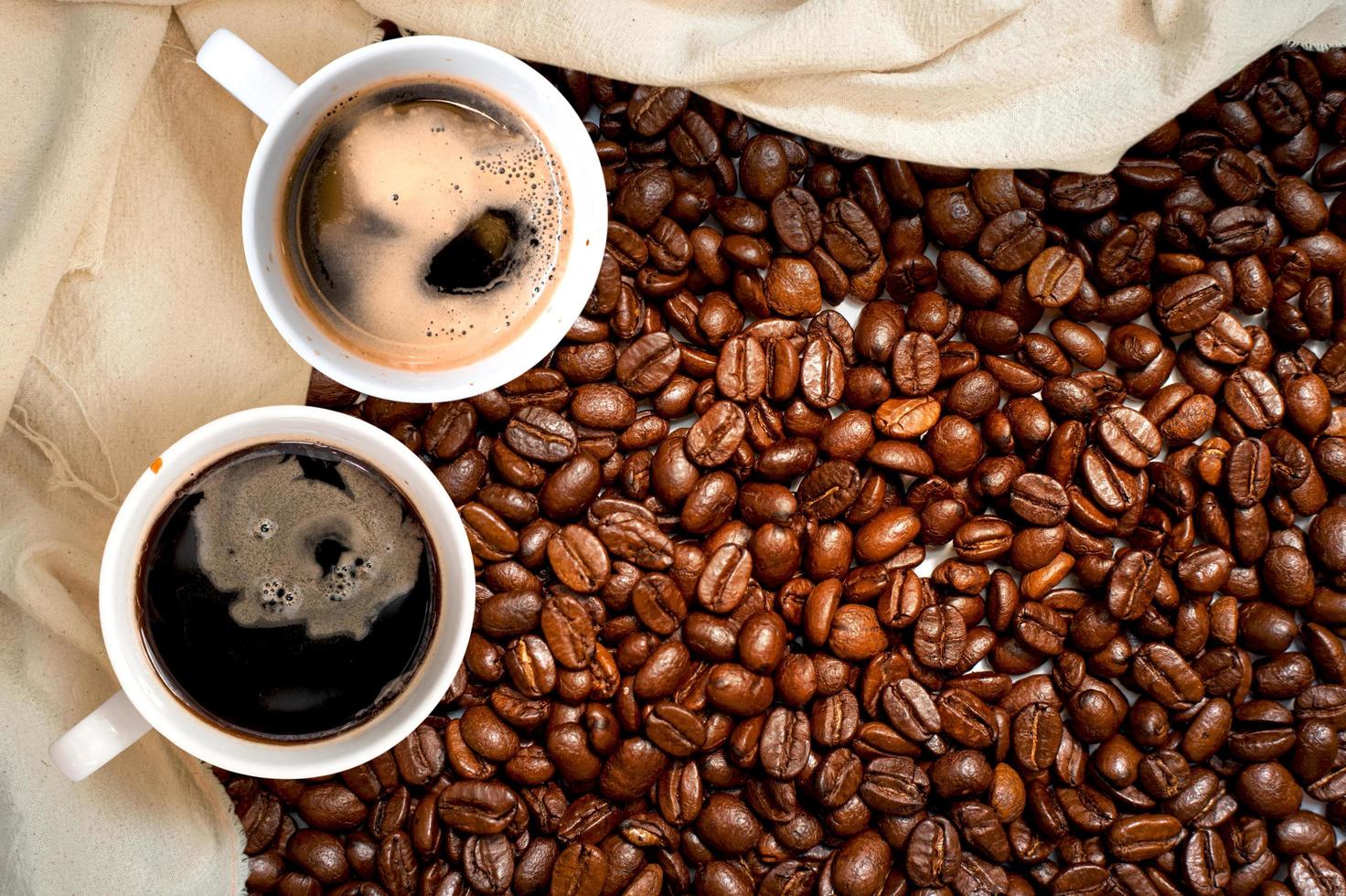 Top view of cup of coffee next to a cloth in pile of coffee beans photo
