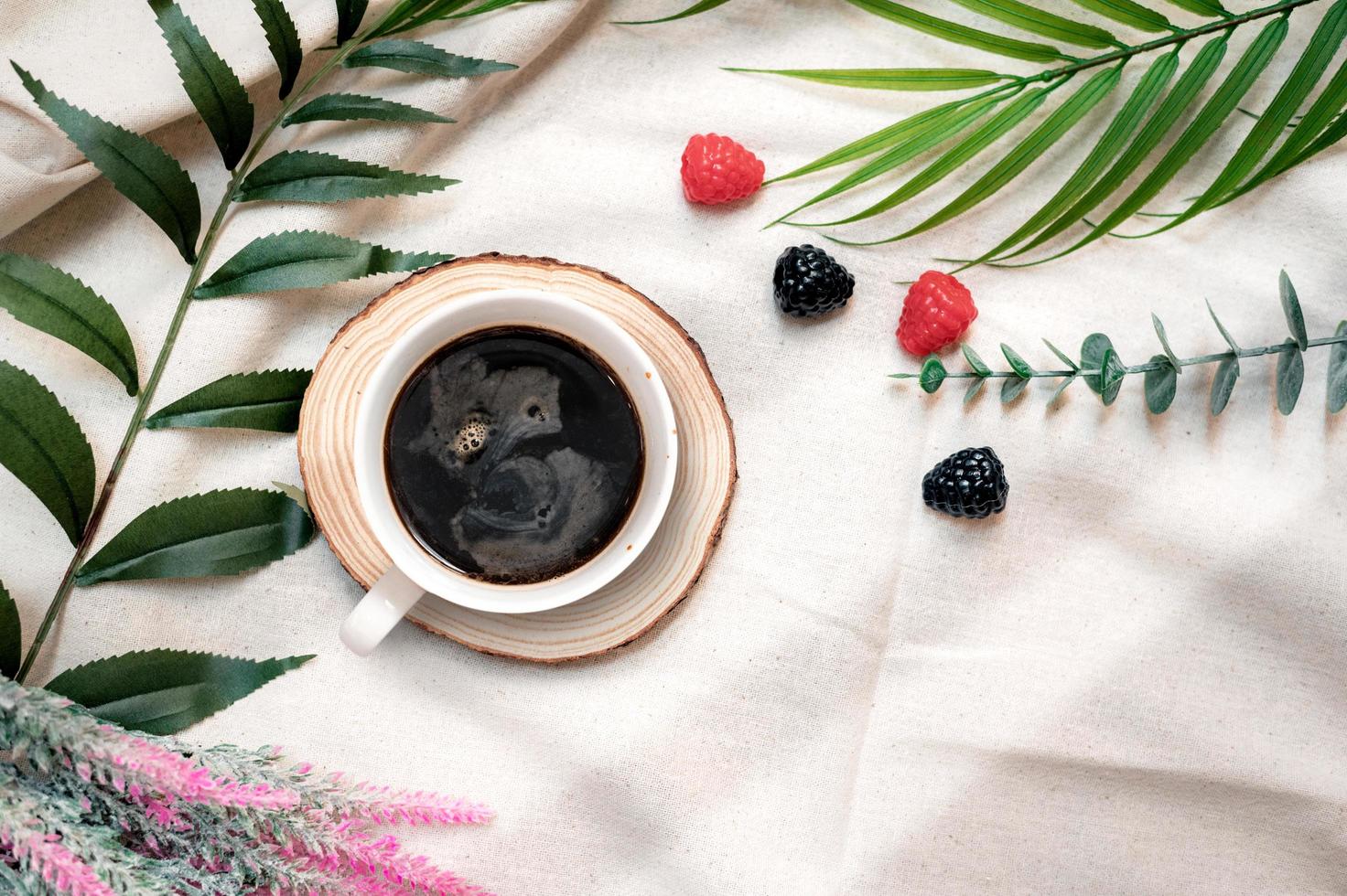 Top view of cup of coffee next to berries on a white tablecloth photo