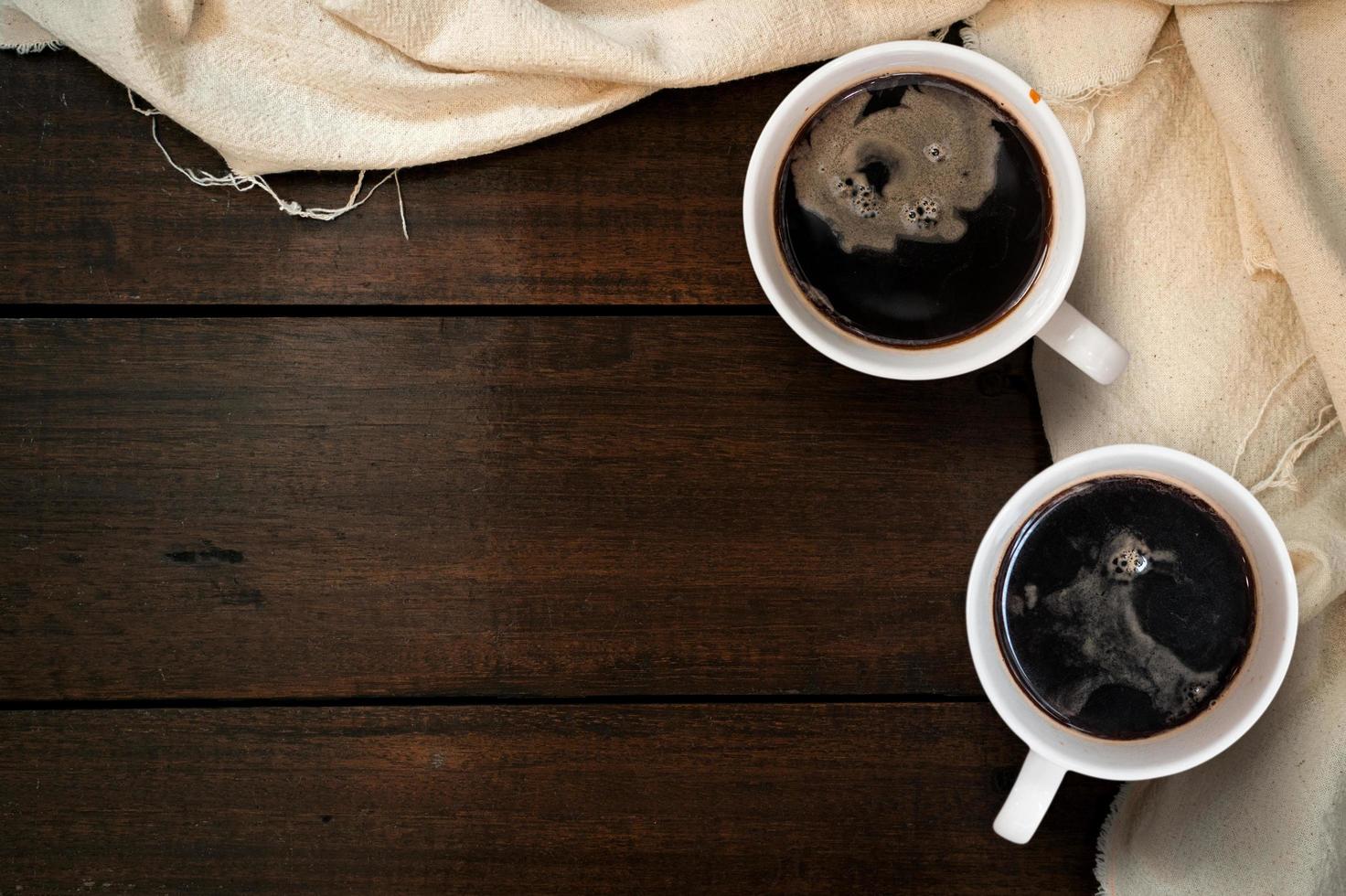 Top view of cup of coffee on a white tablecloth on a wooden tabletop photo