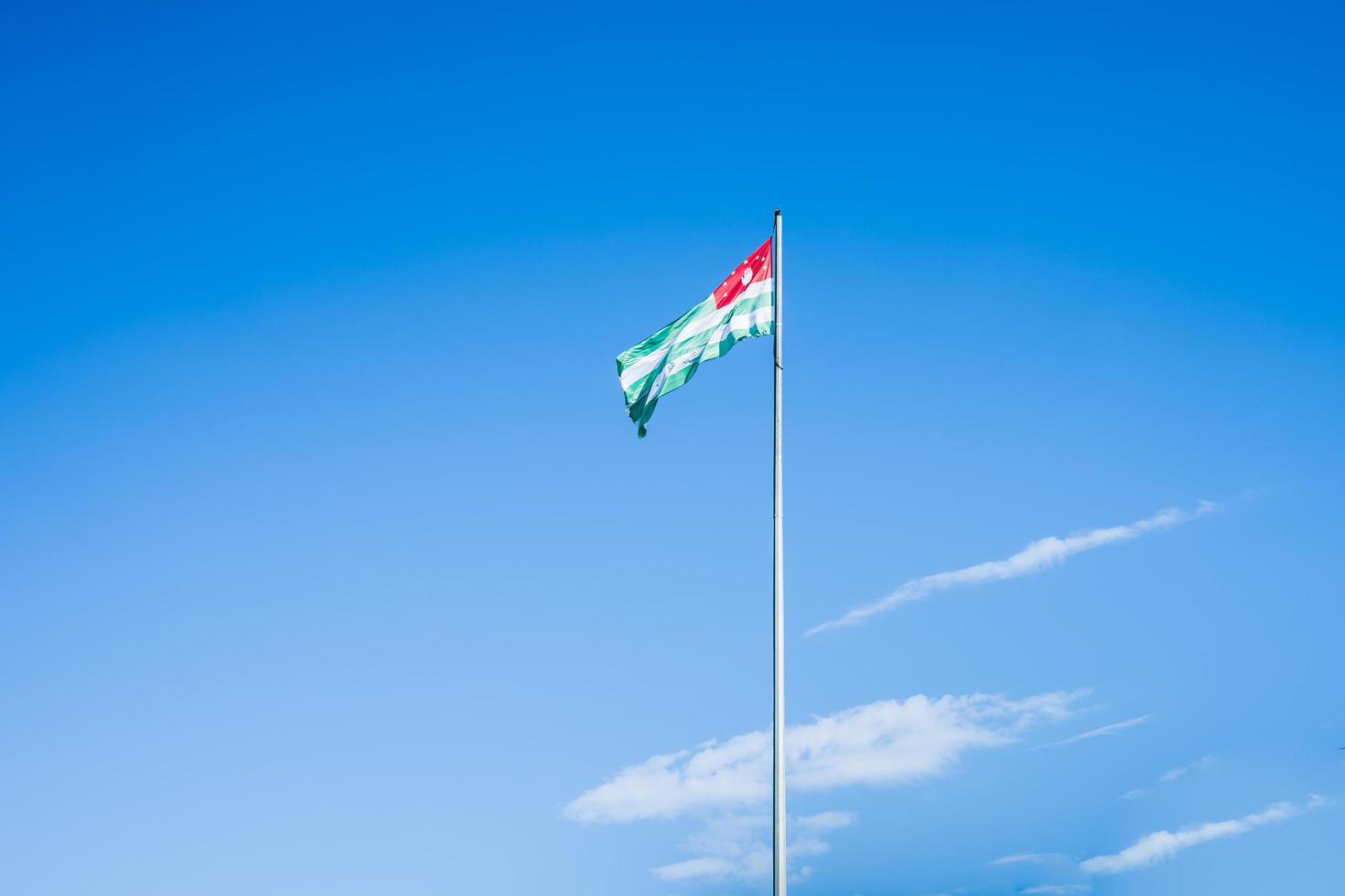 the flag of Abkhazia on the background of blue sky and clouds photo