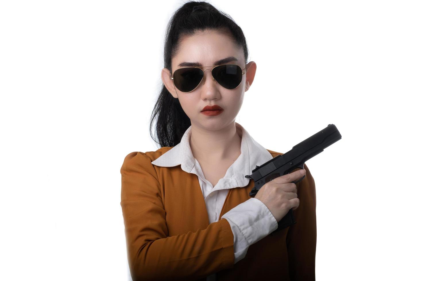 Retrato hermosa mujer asiática vistiendo un traje amarillo con una mano sosteniendo la pistola en el fondo blanco. foto