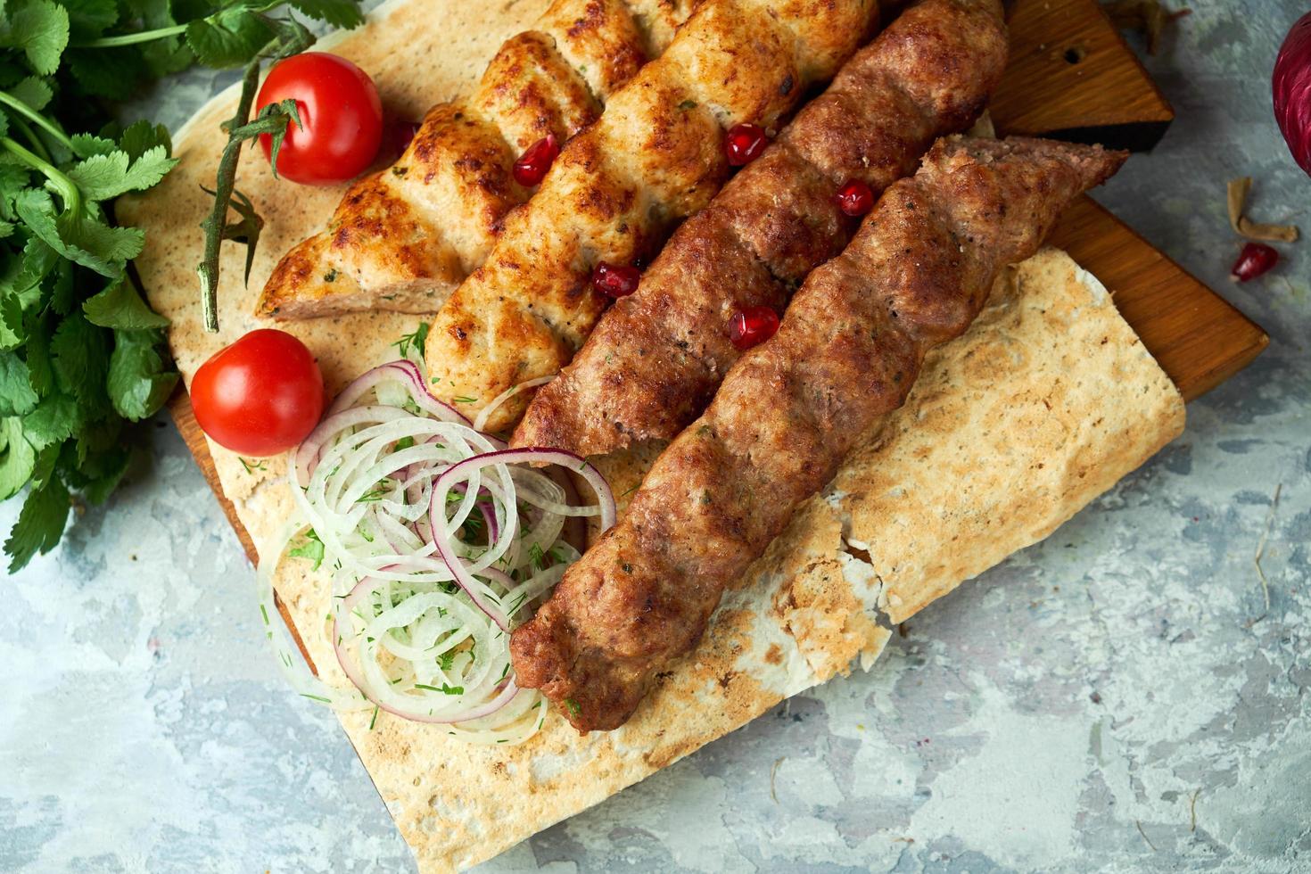 Plates of meat with barbecue and kebab on gray background photo