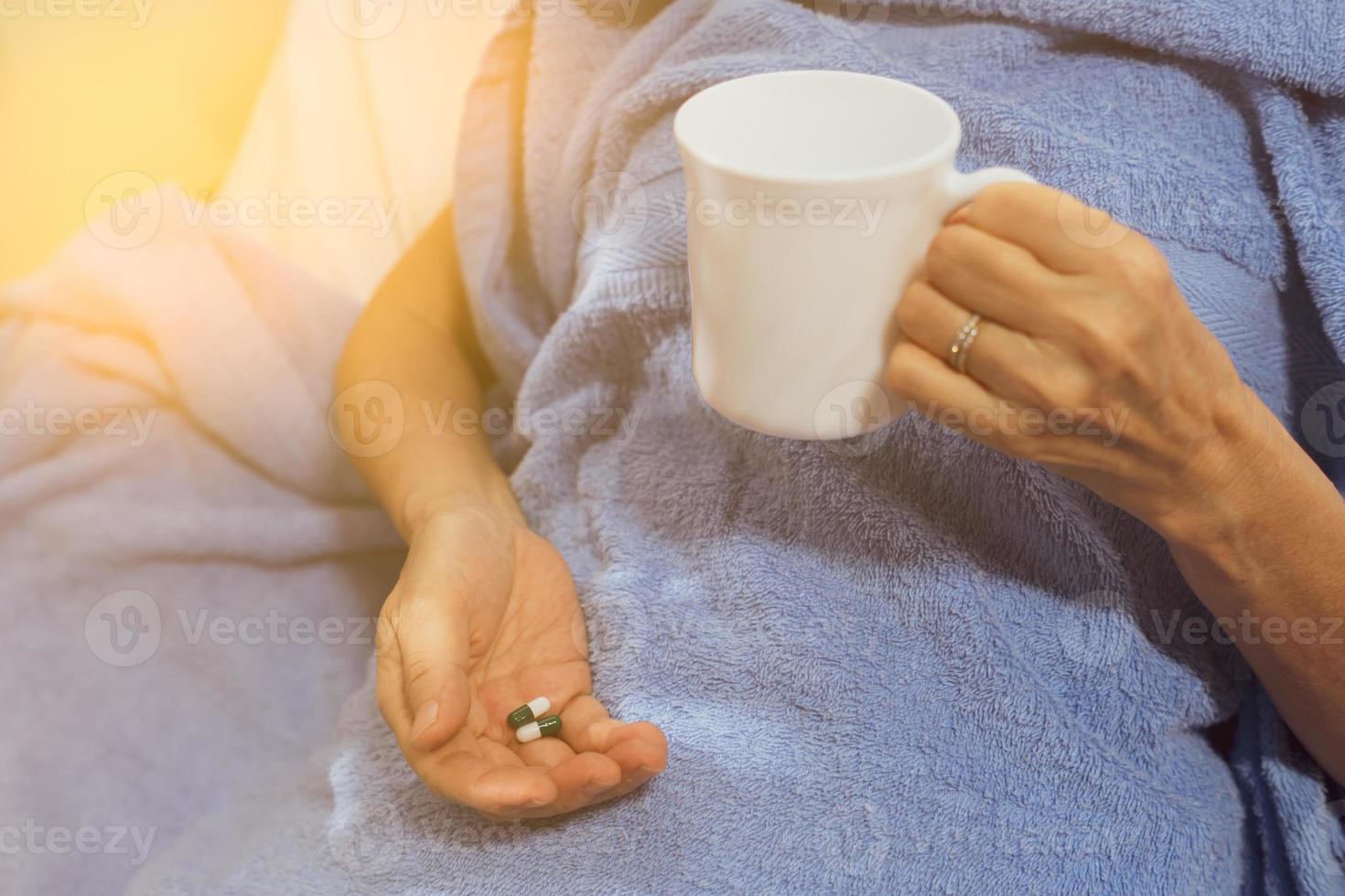 Paciente mayor tomando medicamentos y agua para tratar enfermedades en el hospital. foto