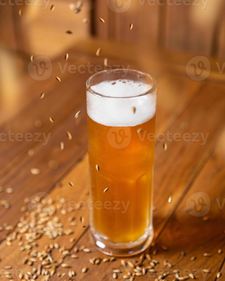 Jarra de cerveza de vidrio con cebada malteada voladora foto