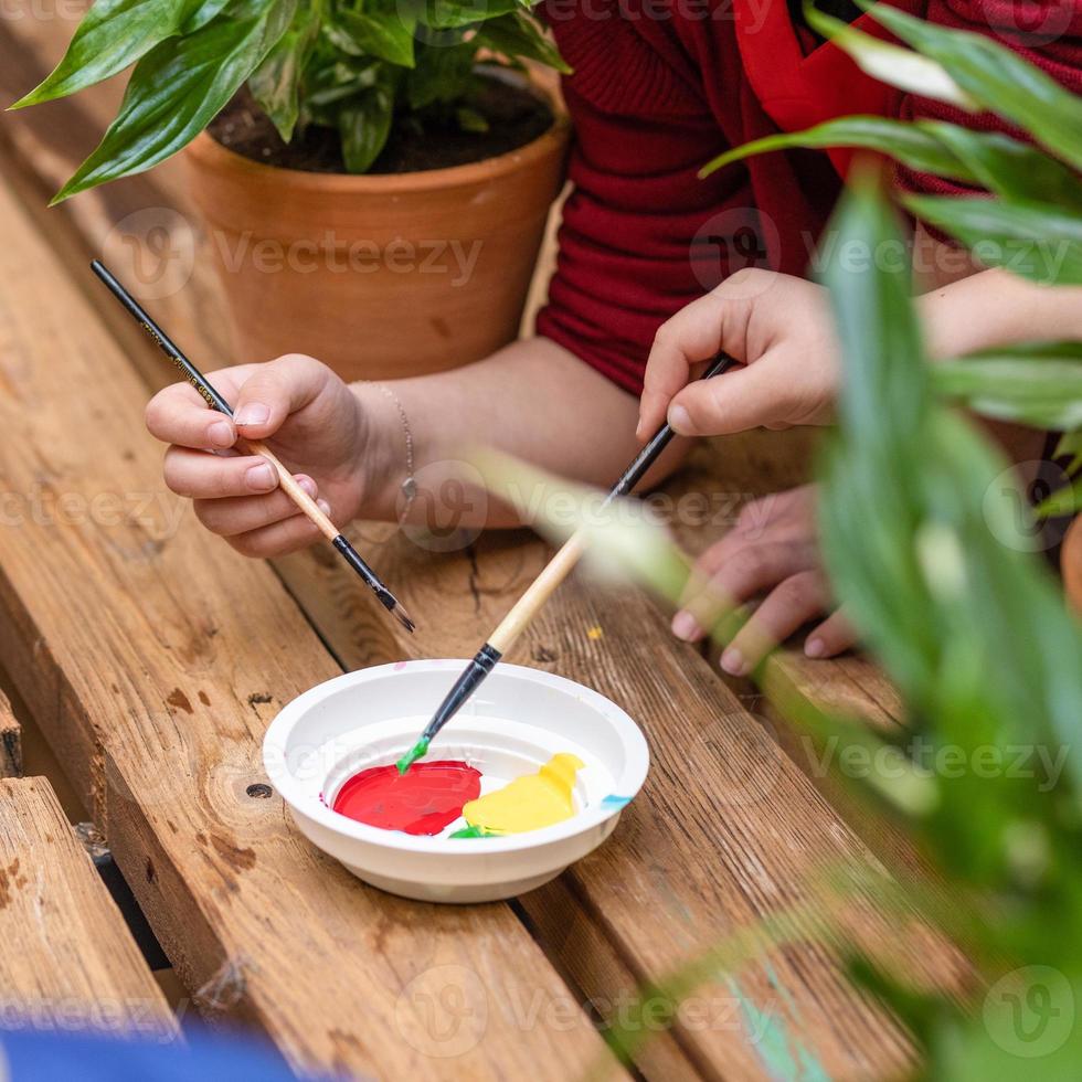 Niños sumergiendo la placa de pintura con una vista superior del cepillo foto