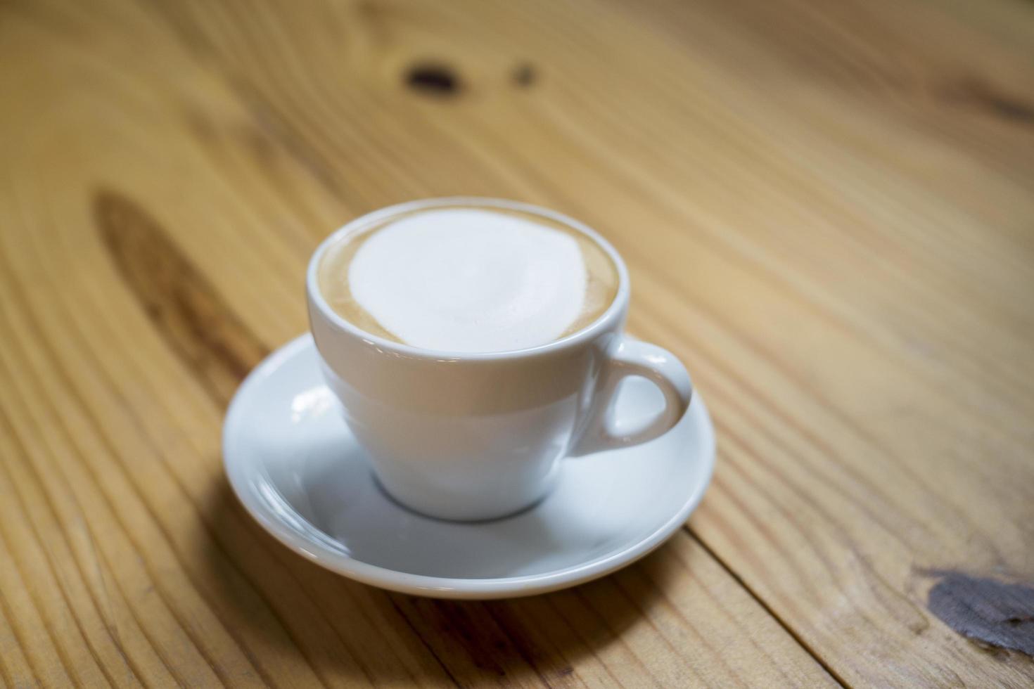 una taza de capuchino caliente en la mesa de madera foto