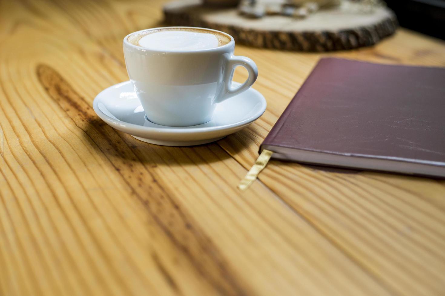 notebook with cup of coffee on wooden desk photo