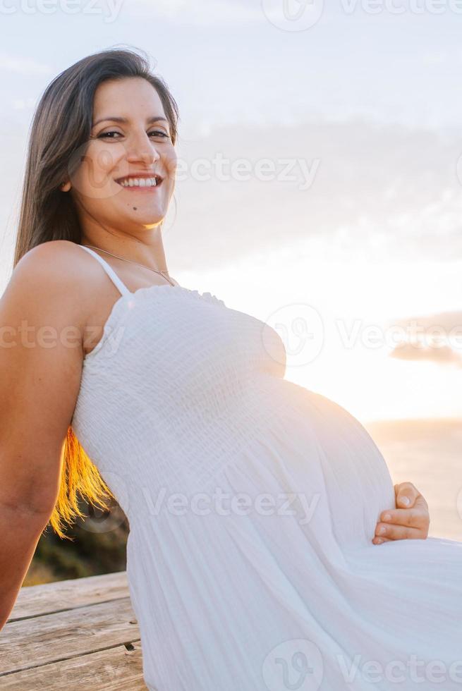 retrato de una mujer embarazada contra un paisaje oceánico foto