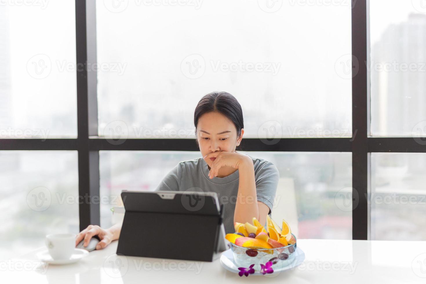 Businesswoman working on laptop with bowl of fresh fruits on table photo