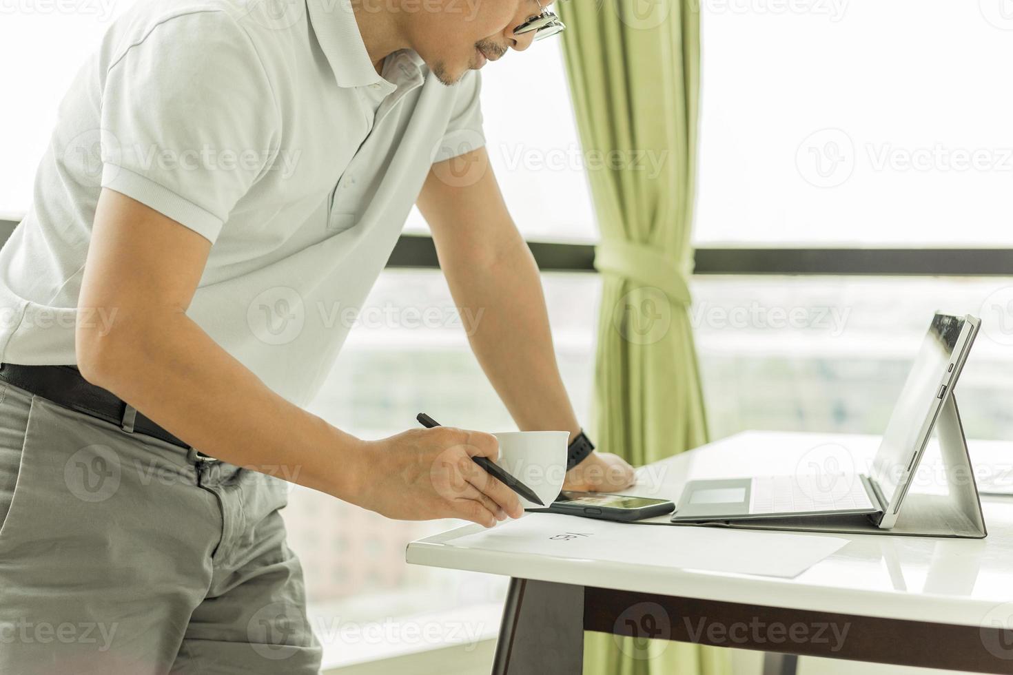 empresario revisando el correo electrónico en la computadora portátil y sosteniendo una taza de café foto