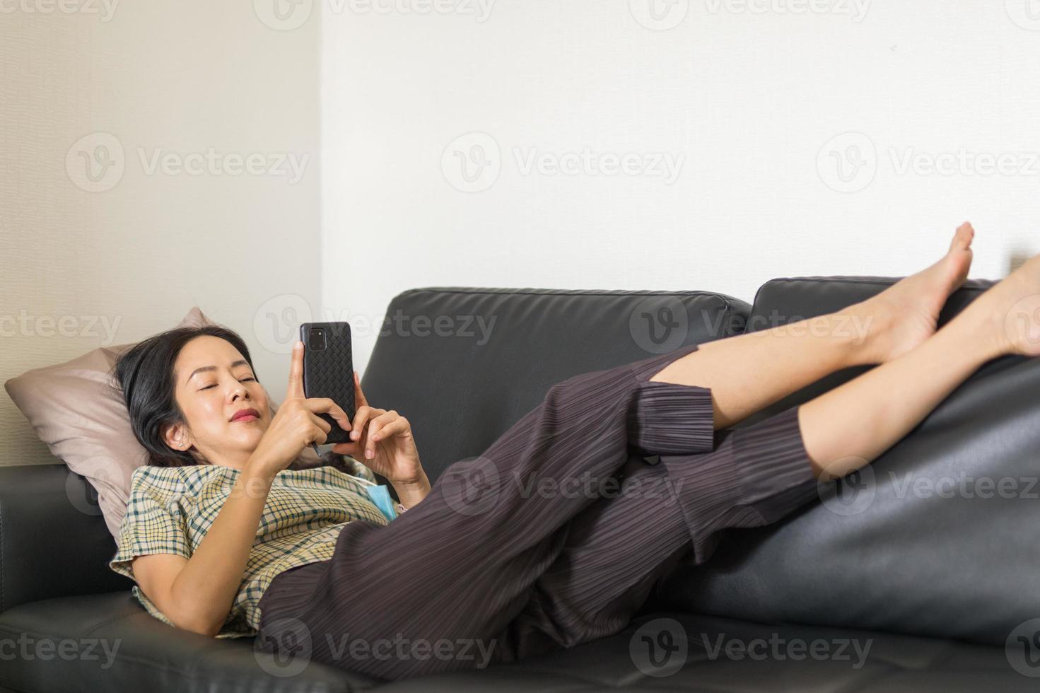 mujer acostada en un sofá con smartphone foto