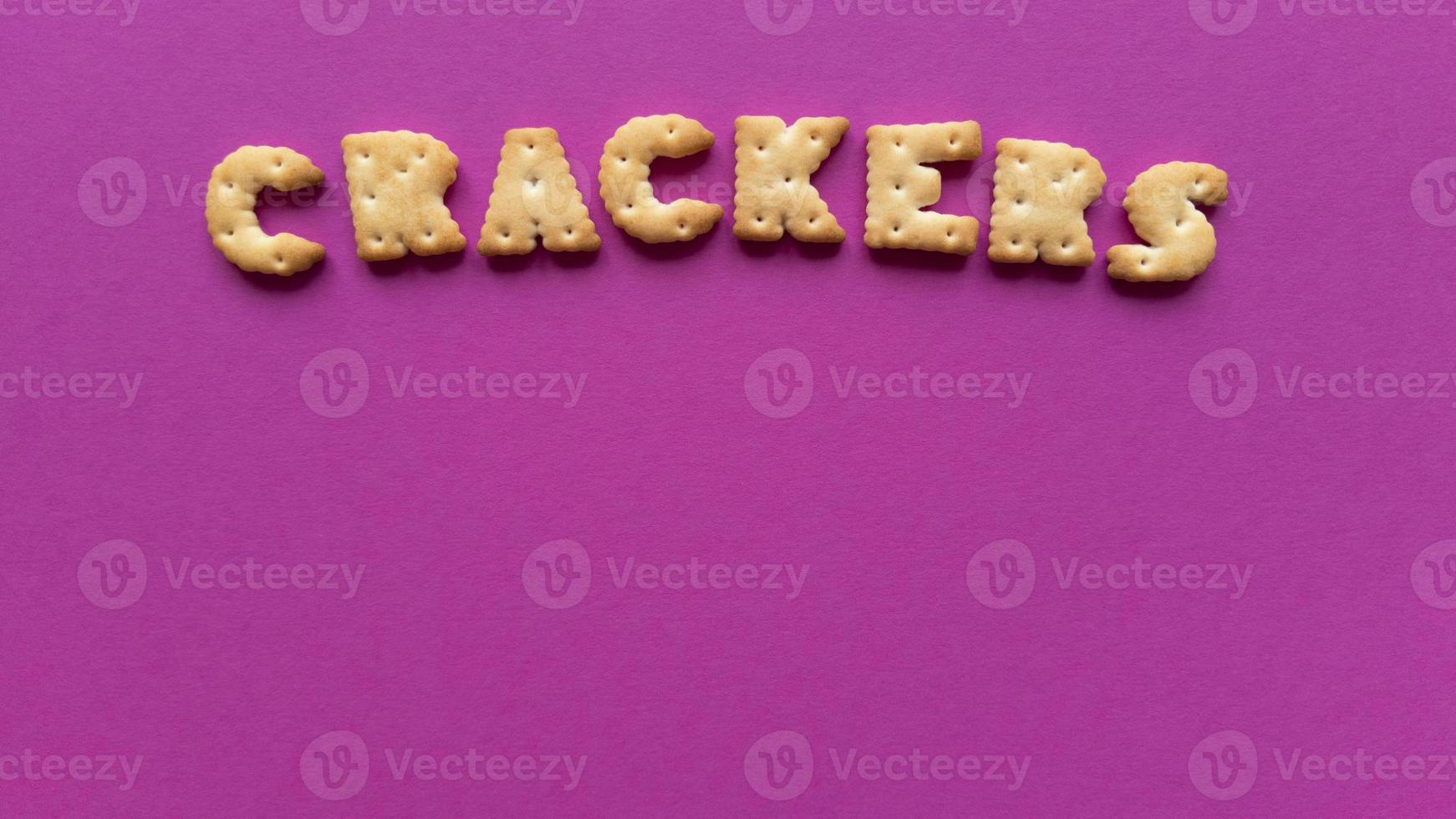 Crackers word on pink background Simple flat lay with pastel texture and copy space Stock photo