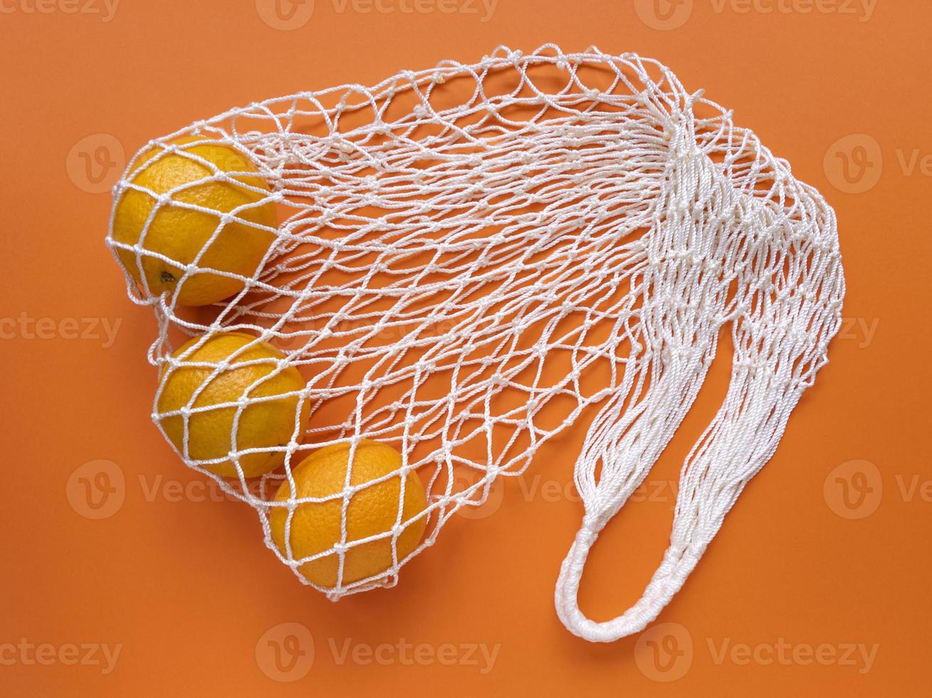 White string cotton eco bag with oranges on orange background Monochrome simple flat lay Ecology zero waste concept Stock photo